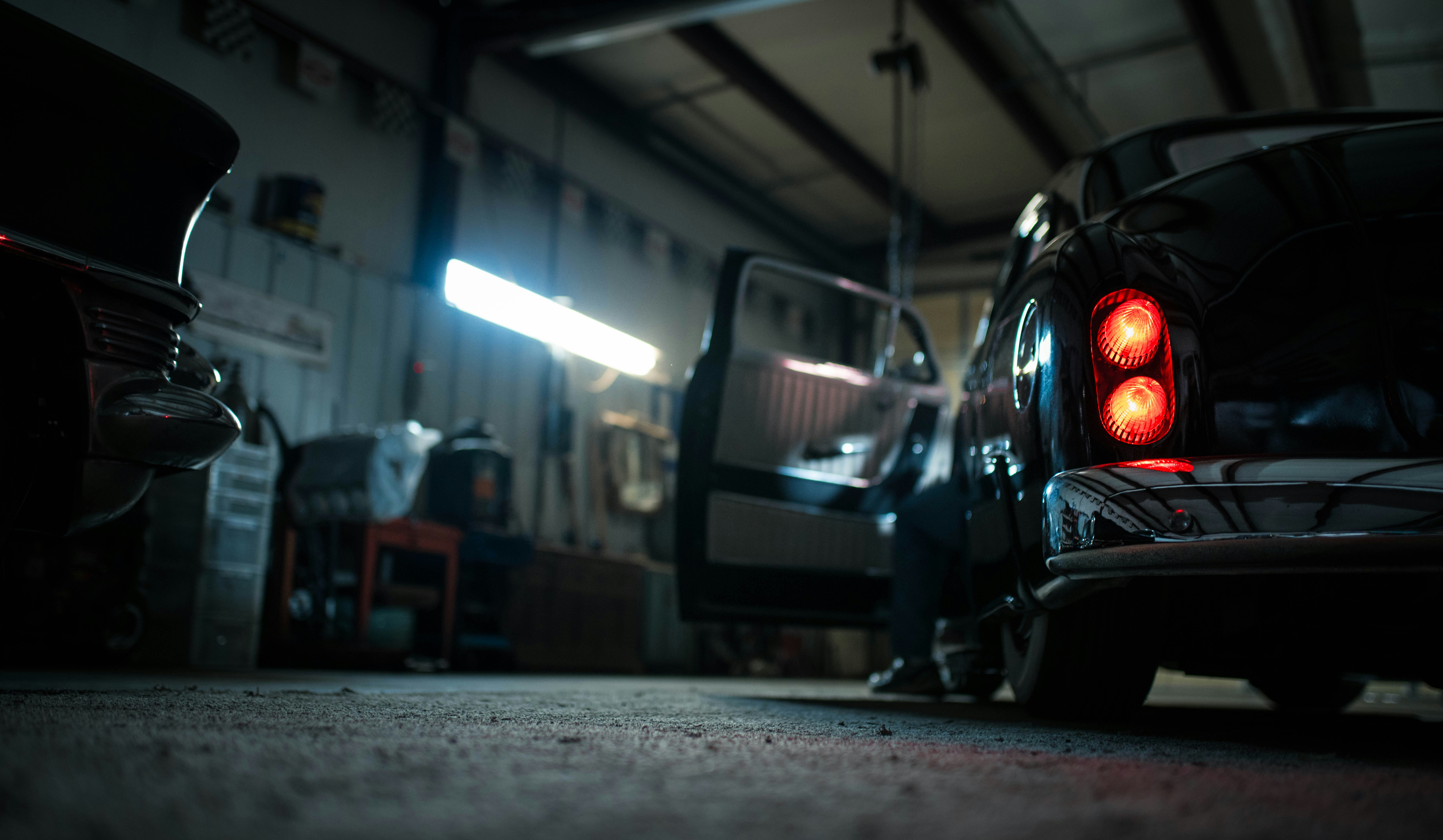 Car in a repair shop with the hood open for service.