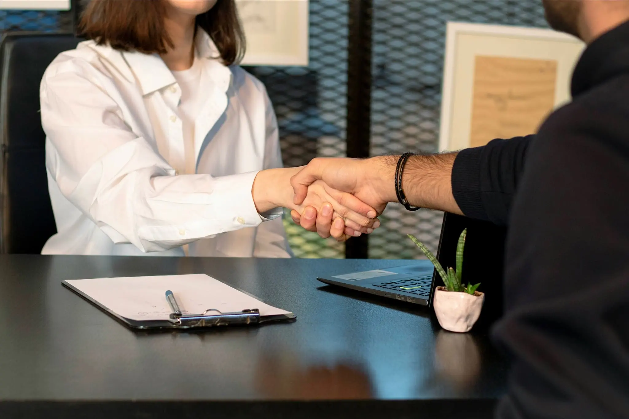 Buyer and seller shaking hands over paperwork for a vehicle bill of sale