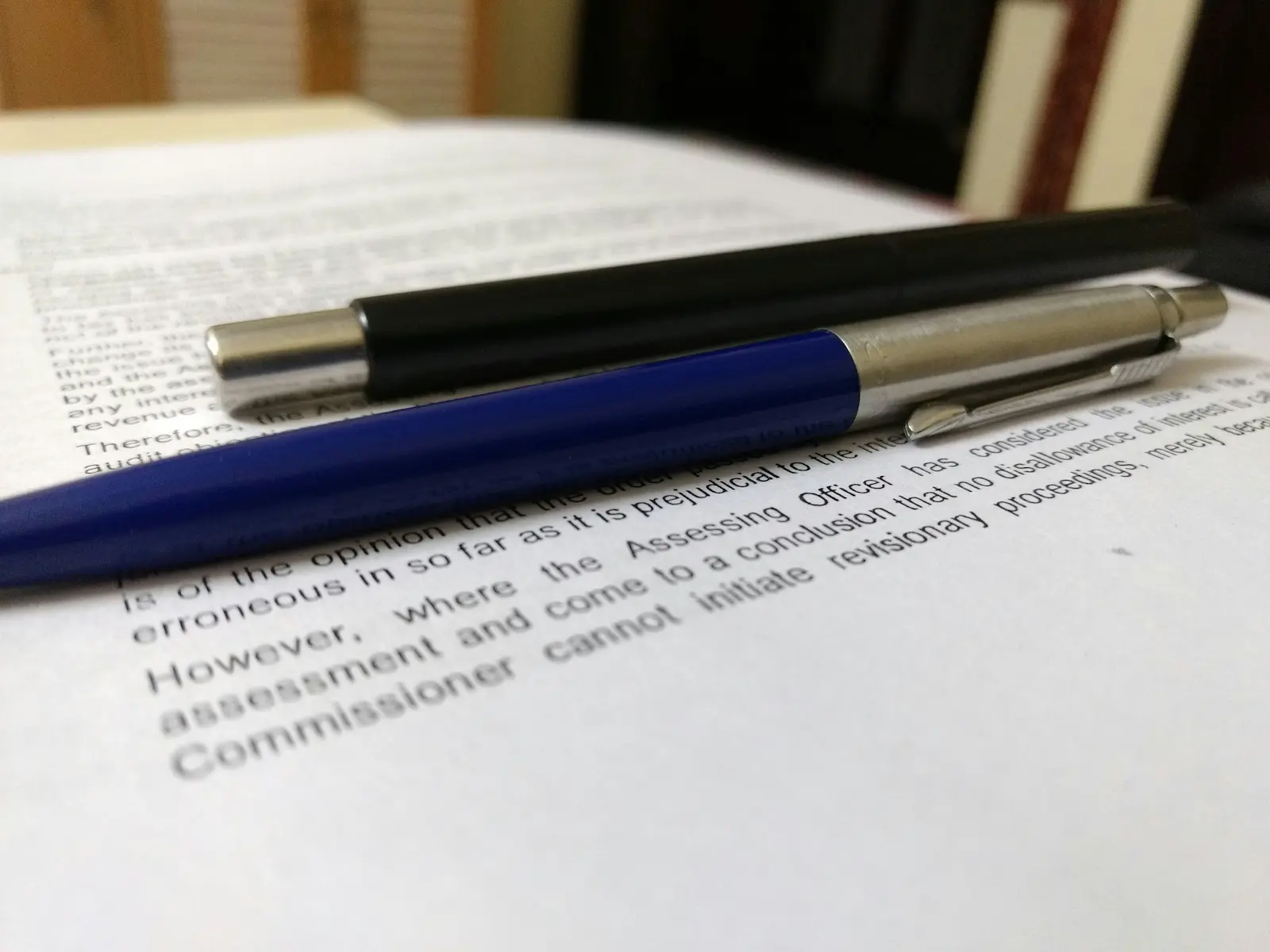 Two pens lying on top of a printed document on a desk.