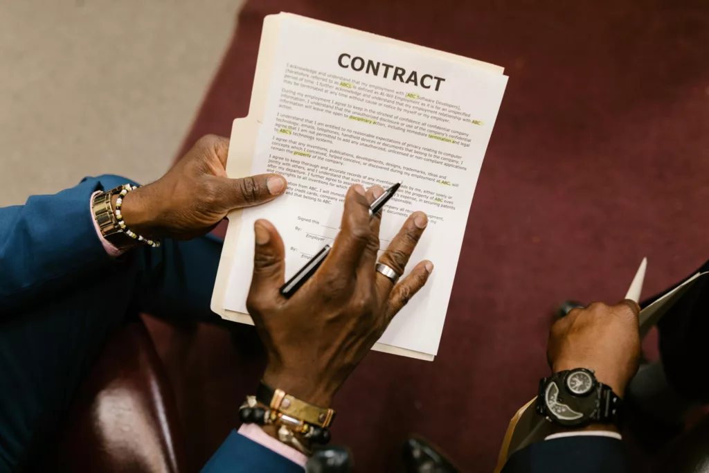Person reviewing a contract document with a pen in hand.