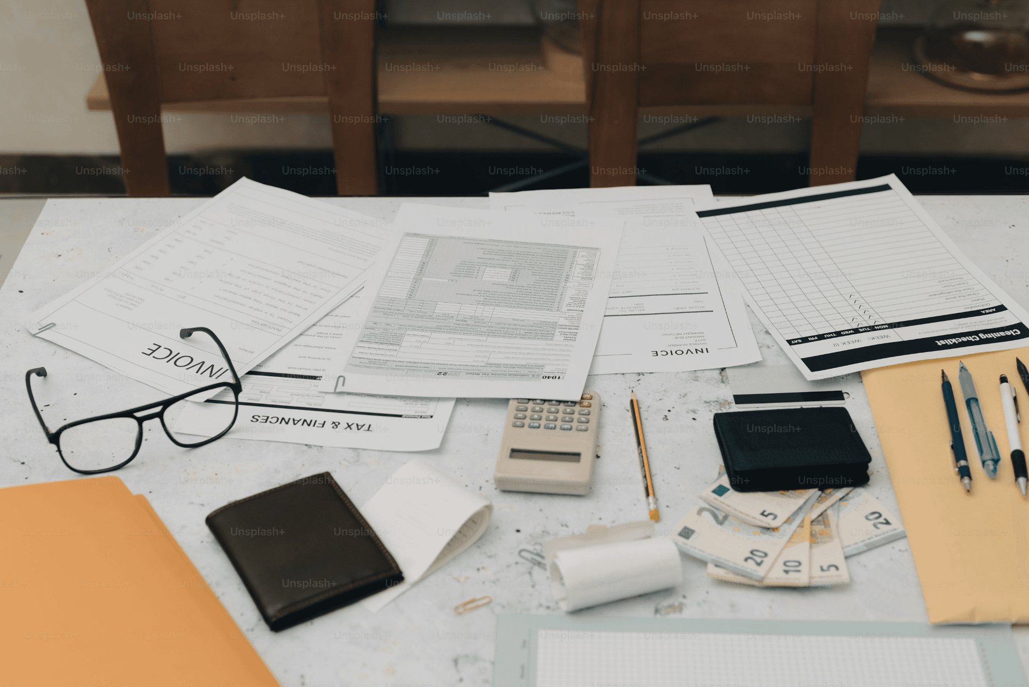 Invoices, documents, calculator, and cash spread across a desk
