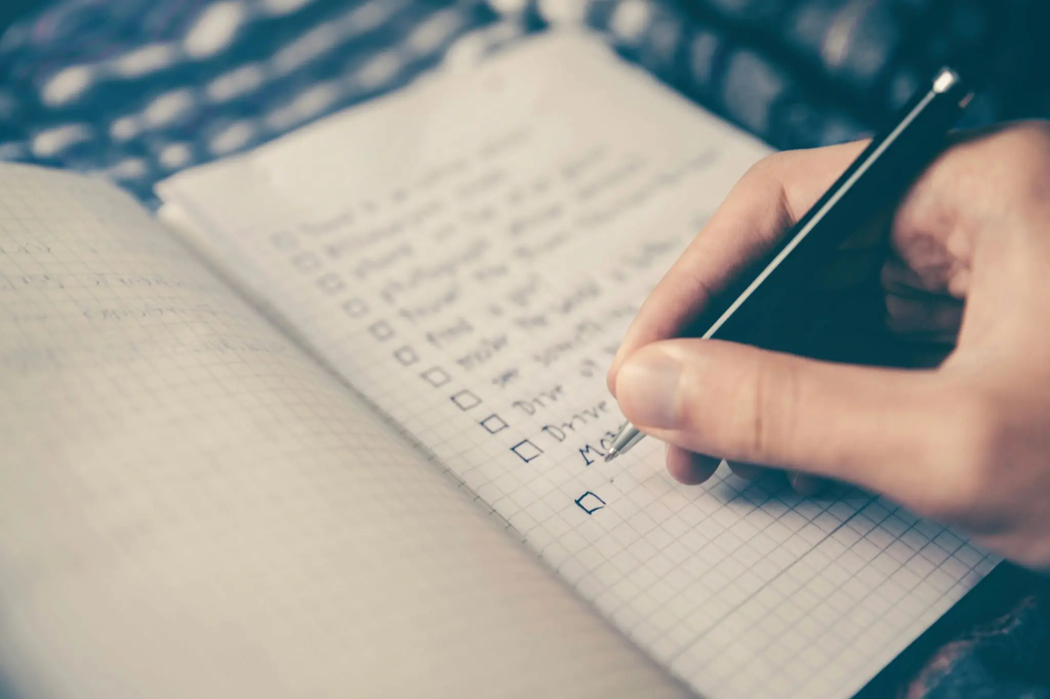 Checklist being written in a notebook for a vehicle bill of sale and car sale paperwork