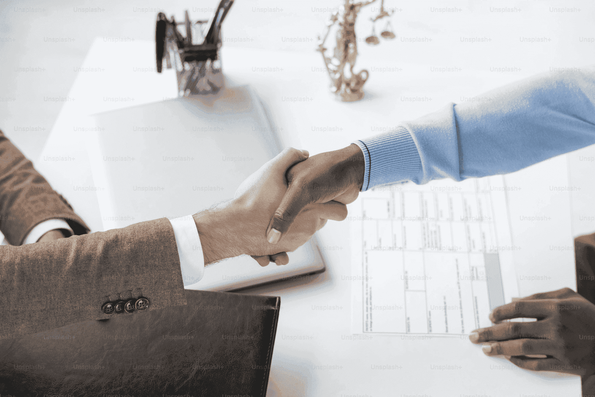 Lawyer and client shaking hands over documents during a consultation