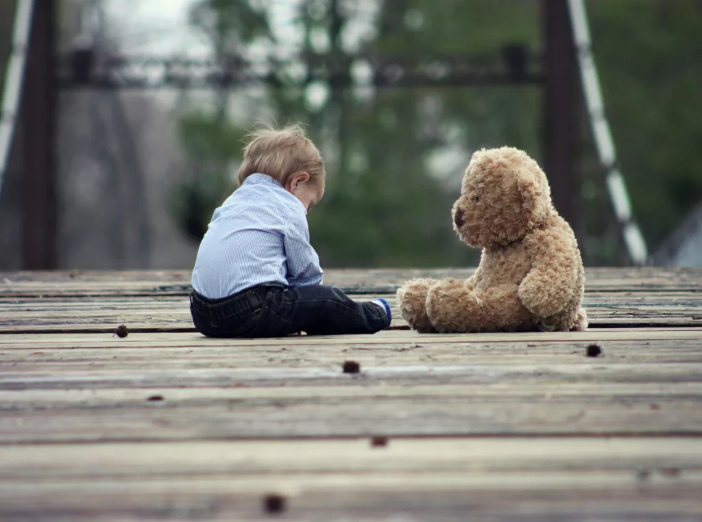 Child custody concept with a toddler sitting next to a teddy bear.