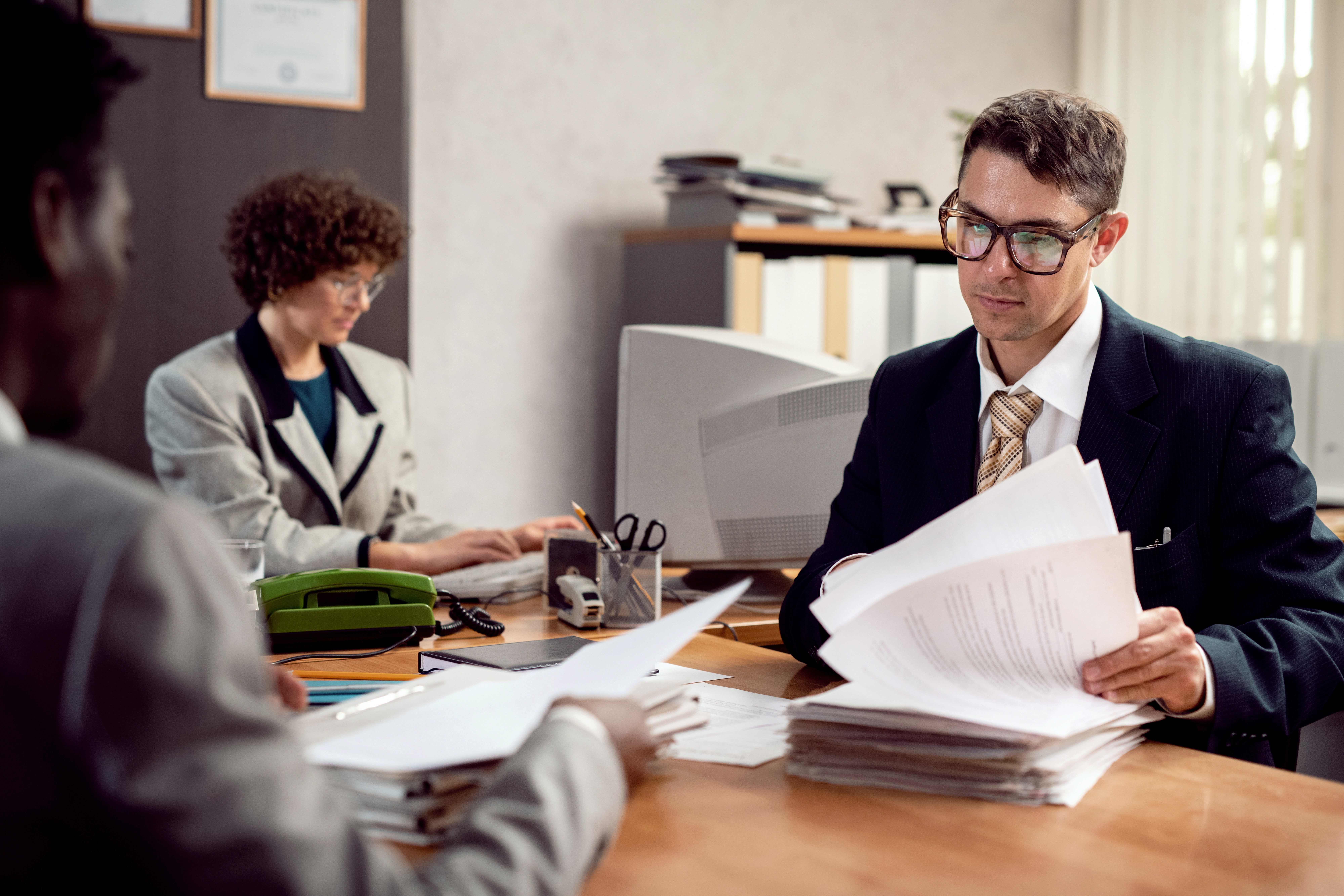 Professional lawyer consultation - attorney and client reviewing documents at desk with laptop and legal papers