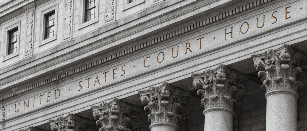Federal courthouse entrance with columns and American flag, professional legal atmosphere