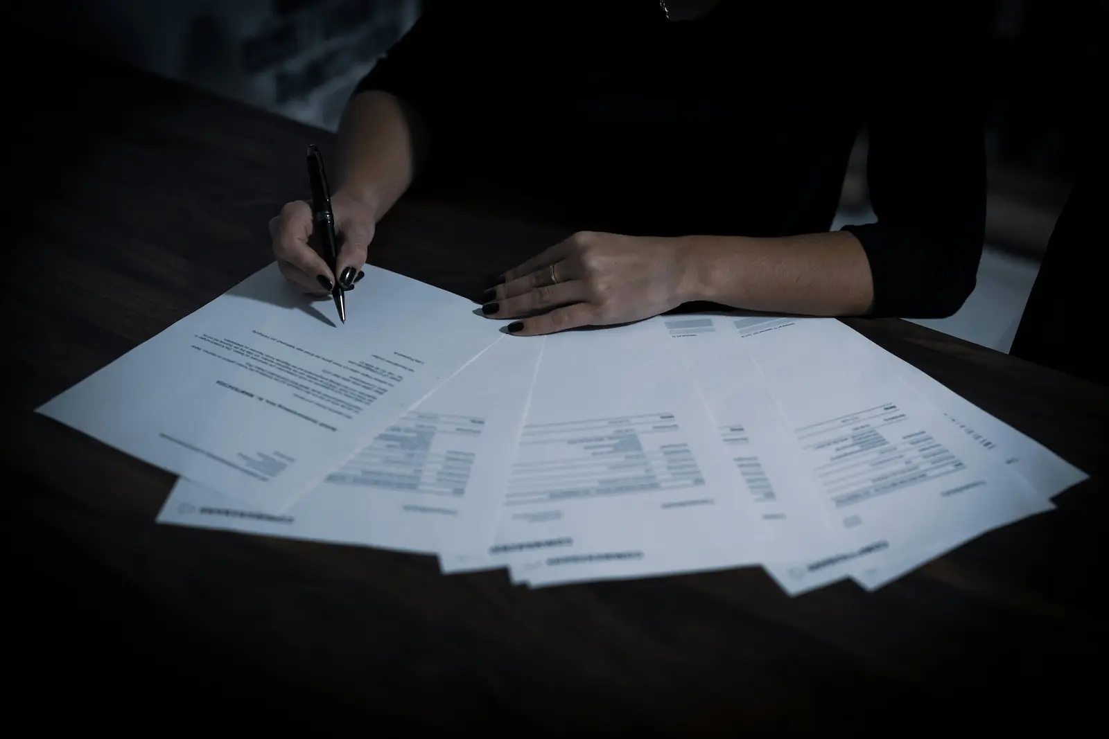 Person reviewing and signing USCIS immigration documents on a desk